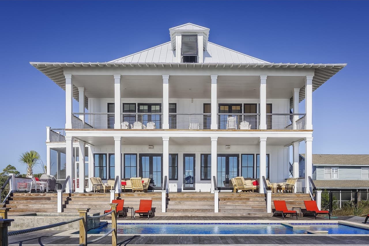 Completed Holden Beach Residence coastal new-build, white wraparound porches overlooking the pool